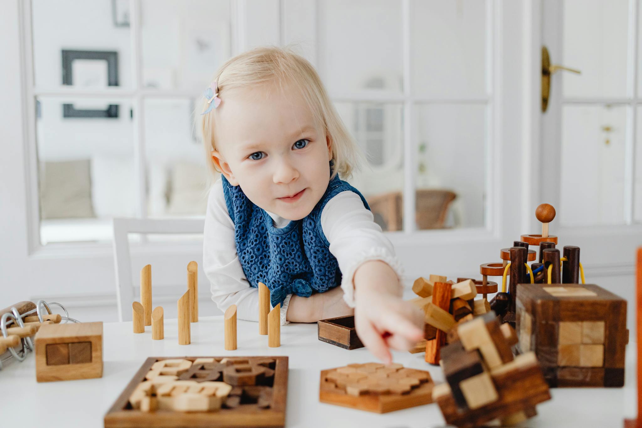 Blonde girl enjoying a creative moment with educational wooden toys indoors.